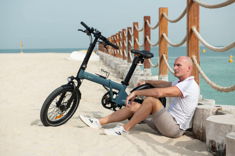 Biyiy Experience - a man sitting by his e-bikes on the beach of Dubai