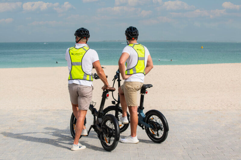 Biyiy Experience - 2 men standing by their e-bikes on the beach of Dubai