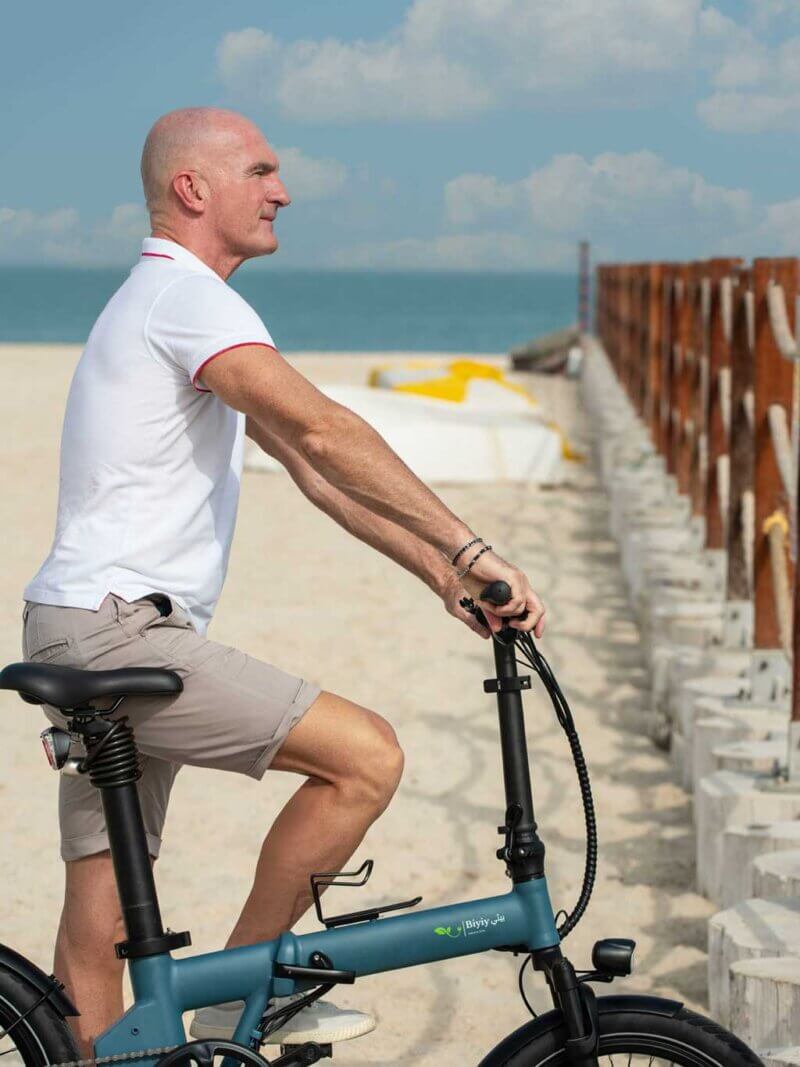 Man standing by bike on the beach in Dubai